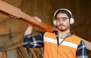 uomo che trasporta legno foto