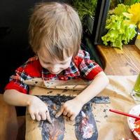 ragazzo disegno il orecchie di un' fatto a mano Pasqua coniglietto fatto di cartone. preparazione per il celebrazione di il Pasqua vacanza. foto