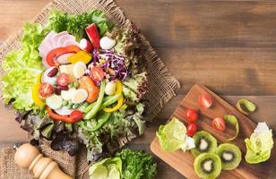 fresco mescolare vegetazione insalata su Marrone legna sfondo foto