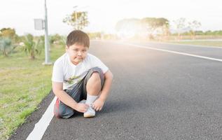 obeso Grasso asiatico ragazzo allacciatura sport scarpa. foto