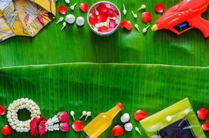 Tailandia Songkran Festival sfondo con acqua pistola, camicia, ghirlanda, profumato acqua e smartphone nel impermeabile Astuccio mettere su Banana foglia. foto