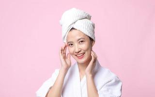 bellissimo giovane asiatico donna contento con pulito viso pelle nel asciugamano e accappatoio, terme completo da uomo su rosa sfondo. cura della pelle, trattamento, benessere terapia, facciale cura, bellezza femmina Salute, cosmetologia concetto foto