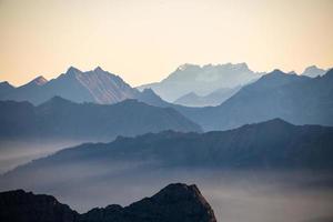 freddo bluastra montagna paesaggio nel nebbia a Alba foto