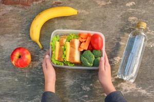 panini, frutta e verdure nel cibo scatola, acqua su vecchio di legno sfondo. superiore Visualizza. foto