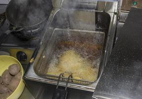 friggitrice per patate con patatine fritte con bollente olio. concetto veloce cibo ristorante, cucina attrezzatura foto