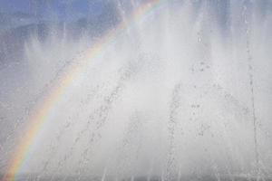 Fontana con un' arcobaleno contro il blu cielo foto