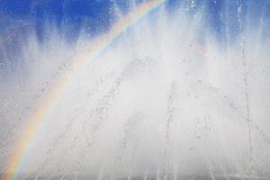 Fontana con un' arcobaleno contro il blu cielo foto