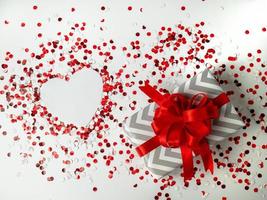 sorpresa regalo. rosso polka punto scatola con bianca arco su sfondo con coriandoli. cuore. il Visualizza a partire dal il superiore foto