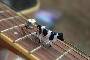 miniatura figura di un' contadino aratura un' campo con il suo mucca su un' chitarra. foto