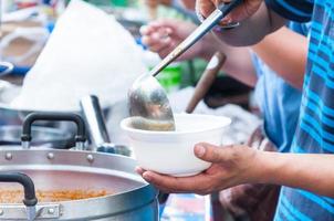 mano Tenere cucchiaio cibo nel il schiuma vassoio ,cibo di strada foto