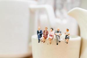 imprenditori in miniatura seduti su una tazza da tè foto
