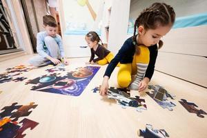 bambini collegamento sega puzzle pezzi nel un' bambini camera su pavimento a casa. divertimento famiglia attività tempo libero. foto