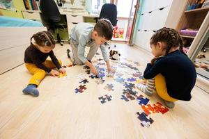 bambini collegamento sega puzzle pezzi nel un' bambini camera su pavimento a casa. divertimento famiglia attività tempo libero. foto