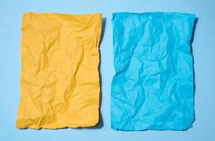Due spiegazzato lenzuola di carta, giallo e blu su un' blu sfondo, spazio per un iscrizione foto