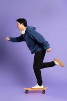 Immagine di giovane asiatico uomo giocando skateboard su viola sfondo foto