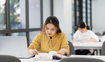 ritratto di asiatico femmina alunno studiando a Università biblioteca foto