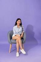 Immagine di ragazza seduta su divano isolato su viola sfondo foto