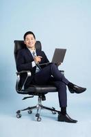 asiatico uomo d'affari maschio ritratto seduta su sedia e isolato su blu sfondo foto