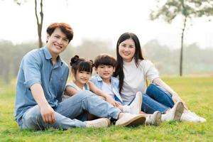 Immagine di un asiatico famiglia seduta insieme su il erba a il parco foto