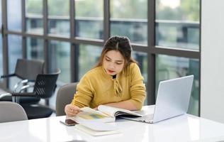 ritratto di asiatico femmina alunno studiando a Università biblioteca foto