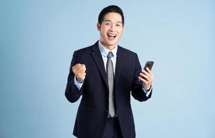 ritratto di uomo d'affari asiatico che indossa tuta su sfondo blu foto