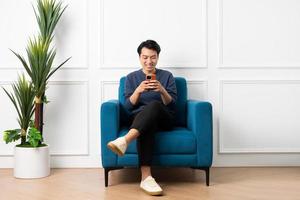 ritratto di asiatico uomo seduta su divano a casa foto