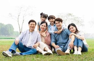 Immagine di un asiatico famiglia seduta insieme su il erba a il parco foto