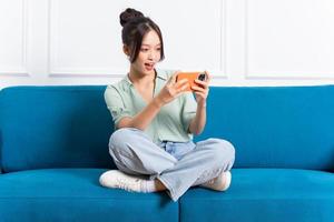 Immagine di giovane asiatico ragazza seduta su divano a casa foto
