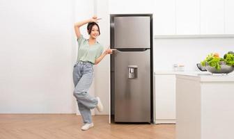asiatico donna in piedi Il prossimo per il frigorifero nel il cucina foto