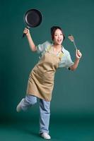 asiatico donna indossare grembiule e Tenere un' padella foto