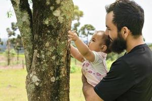 carino bambino abbracciare un' albero tronco nel il primavera foresta. foto