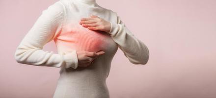 donna mani controllo granuli su sua Seno per segni di Seno cancro su rosa sfondo. assistenza sanitaria mondo Salute giorno concetto. foto