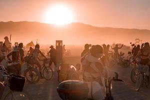 persone a piedi in direzione tramonto a un' Festival nel il deserto a il ardente uomo Festival. foto