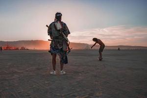 persone a piedi in direzione tramonto a un' Festival nel il deserto a il ardente uomo Festival. foto