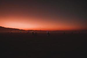 persone a piedi in direzione tramonto a un' Festival nel il deserto a il ardente uomo Festival. foto