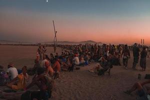 persone a piedi in direzione tramonto a un' Festival nel il deserto a il ardente uomo Festival. foto