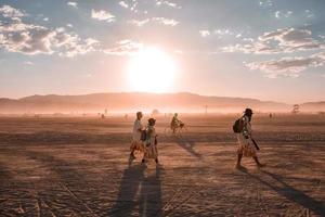 persone a piedi in direzione tramonto a un' Festival nel il deserto a il ardente uomo Festival. foto