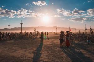 persone a piedi in direzione tramonto a un' Festival nel il deserto a il ardente uomo Festival. foto