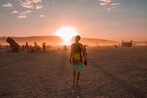 persone a piedi in direzione tramonto a un' Festival nel il deserto a il ardente uomo Festival. foto