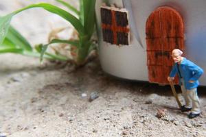 miniatura figura di un' nonno chi è in attesa nel davanti di il Casa. foto