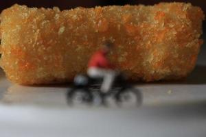 un' miniatura figura di un' ciclista equitazione accanto il torta e su il piatto. foto