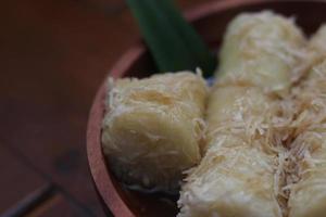 un' vicino su di lupi con grattugiato Noce di cocco e Marrone zucchero salsa servito nel un' di legno ciotola. indonesiano tradizionale cibo foto concetto.