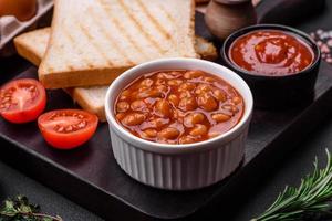 delizioso in scatola fagioli nel un' pomodoro nel un' bianca ceramica ciotola foto