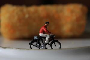 un' miniatura figura di un' ciclista equitazione accanto il torta e su il piatto. foto