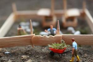 un' vicino su di miniatura figura di un' capra Herder alimentazione nel un' di legno gabbia. pastore concetto. foto