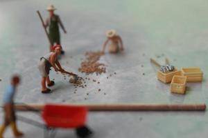 miniatura figure di lavoratori Lavorando insieme per mossa grano. foto