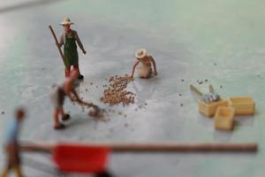 miniatura figure di lavoratori Lavorando insieme per mossa grano. foto