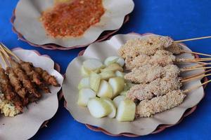 foto di pollo satay impanato e servito con rosso chili salsa. indonesiano cibo chiamato saziare taichan. cibo concetto foto.