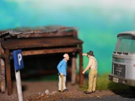 un' vicino su di un' miniatura figura di un vecchio uomo parlando per altro persone nel un vecchio edificio di il lato di il strada. foto