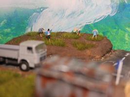 un' miniatura diorama di un' riso campo e un' strada come bene come parecchi persone e veicoli e edifici. foto